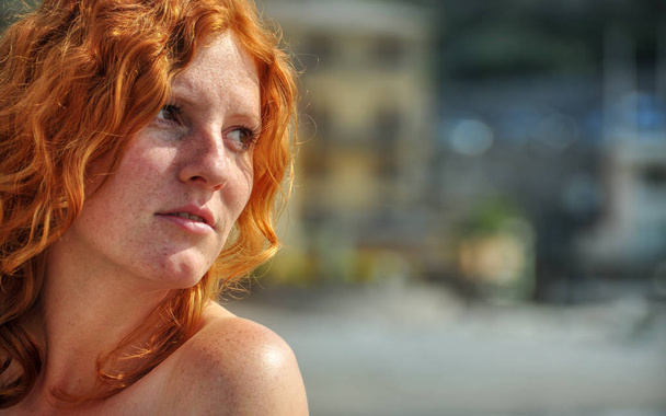 Hermoso retrato en primer plano de una joven mujer rizada de pelo rojo elegante junto al mar en el pueblo pesquero de Italia con espacio para copiar, lugar para el texto
 - Foto, imagen