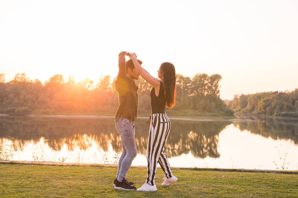 Romantic, social dance and people concept - young couple dancing bachata on the background of sunset - Фото, изображение