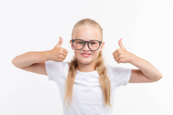 Gyönyörű gyermek lány mutatja a elszigetelt fehér remek szemüveg - Fotó, kép