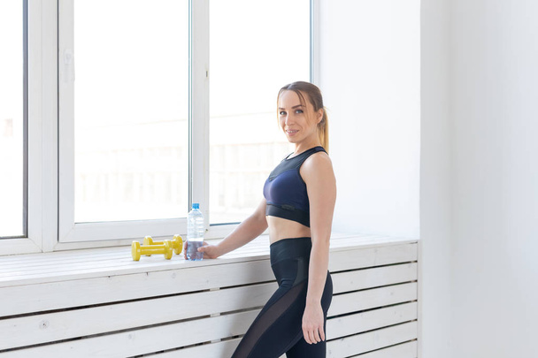Тренування, фітнес і спортивна концепція - красива спортивна жінка, що стоїть біля вікна в спортзалі
 - Фото, зображення