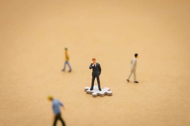 Miniatur-Menschen Geschäftsleute stehen auf weißen Puzzles. die Wandleuchte - Foto, Bild