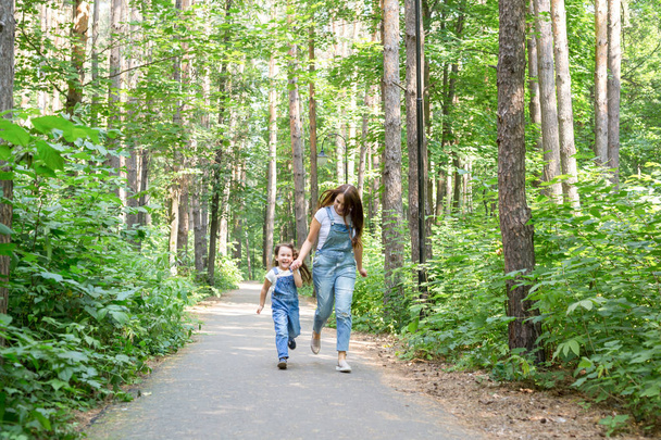 Familien-, Natur- und Menschenkonzept - Mutter und süße kleine Tochter verbringen Zeit miteinander beim Waldspaziergang - Foto, Bild