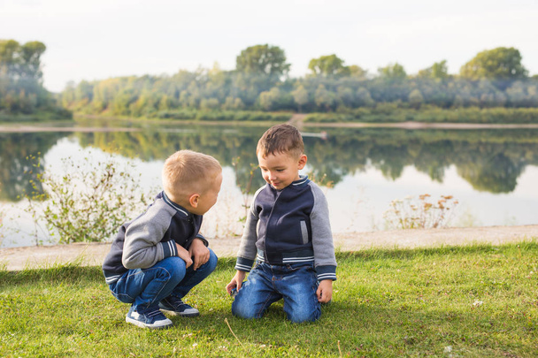 子どもと自然 - 自然の背景の上、草の上に座って 2 人の兄弟の概念 - 写真・画像