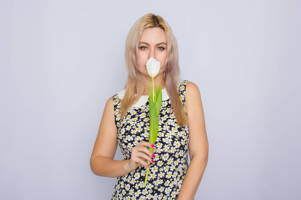 Blonde woman holding one white tulip - Фото, зображення