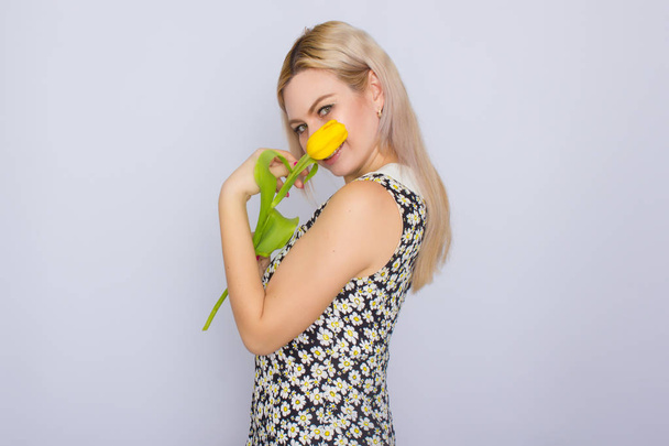 Blonde woman holding one yellow tulip - Zdjęcie, obraz