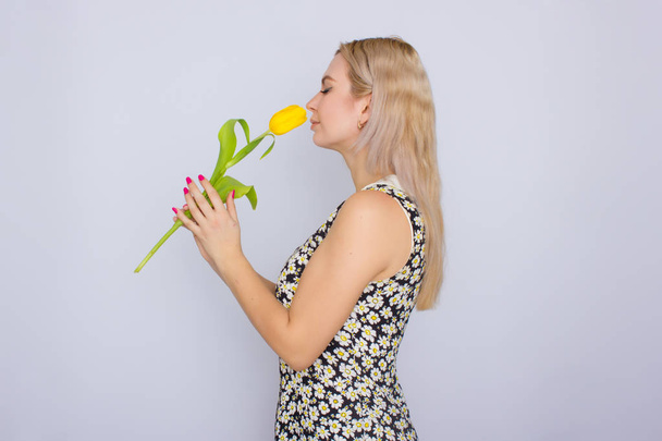Blonde woman holding one yellow tulip - Foto, afbeelding
