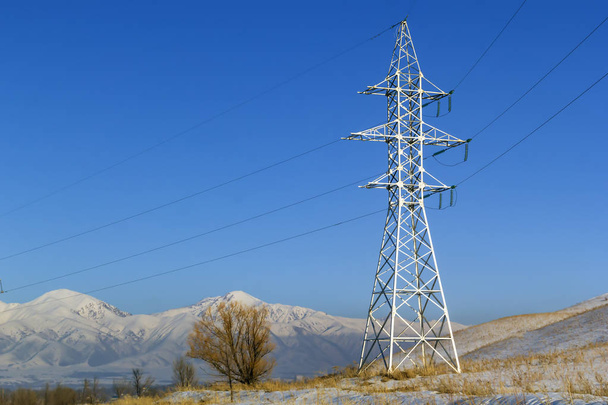 Electricity pole against the blue sky and snowy mountains. Copy space - Photo, Image
