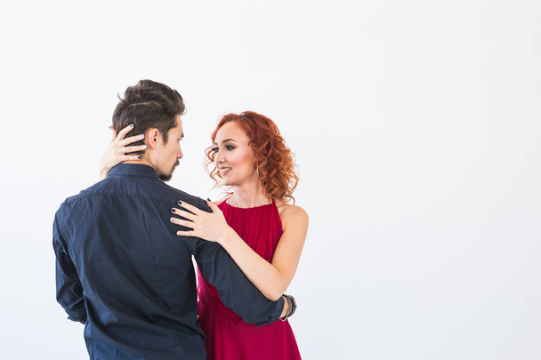 Romantic, social dance, people concept - couple dancing bachata in the studio, man hugging the woman from her back. Background with copy space - Φωτογραφία, εικόνα