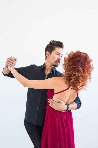 Social dance, bachata, kizomba, salsa, tango concept - Woman dressed in red dress and man in a black costume over white background - Valokuva, kuva