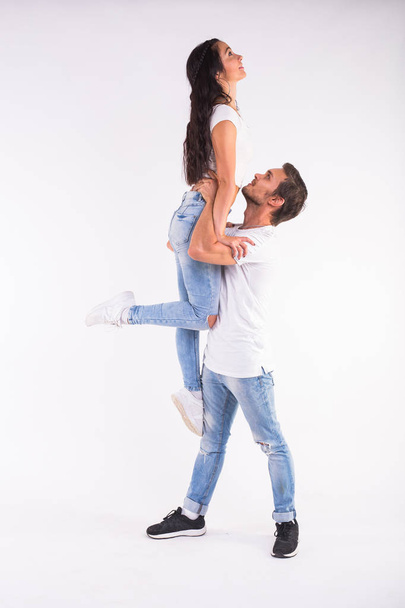 Jeune couple dansant danse sociale bachata, merengue, salsa, kizomba. Deux pose d'élégance sur chambre blanche
. - Photo, image
