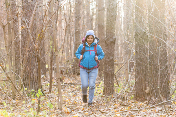 People, hike and nature concept - Female tourist walking in the autumn forest - Foto, imagen