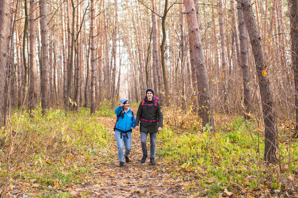 Travel, tourism, hike and people concept - Couple with backpacks walking in the autumn forest - Φωτογραφία, εικόνα