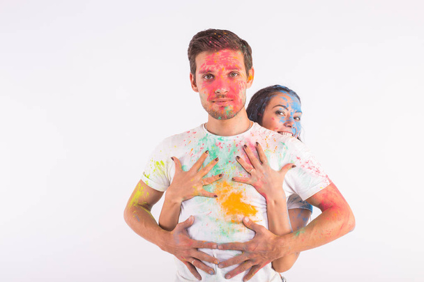 Vacances, holi et concept de personnes - Couple heureux s'amuser avec de la poudre multicolore sur leurs visages sur fond blanc
 - Photo, image