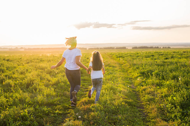 Concepto de familia, verano y vacaciones - hija pequeña y madre corren en el campo de verano
 - Foto, imagen