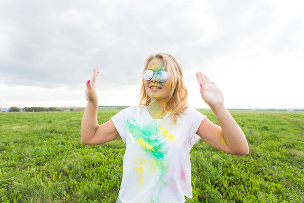 Веселье, праздник и праздник - Забавная женщина, покрытая цветным порошком, улыбается на фоне природы
 - Фото, изображение