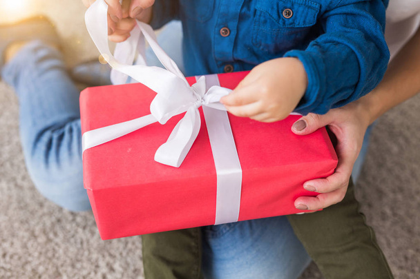 Present, children, birthday and holiday concept - little child boy unpacking gift box with mom - Foto, afbeelding