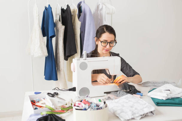 mensen, naaister, kleermaker en fashion concept - jonge mode-ontwerper in haar showroom - Foto, afbeelding