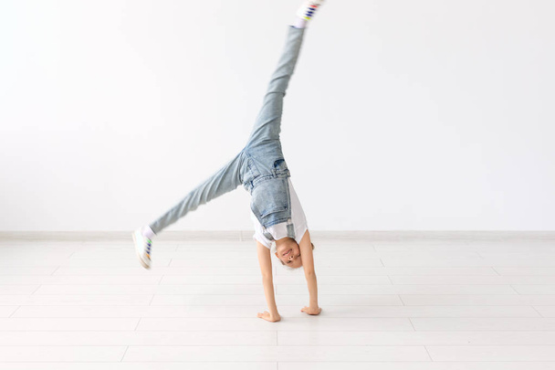 lidé, sport a děti koncept - hezká holčička dělá gymnastiku nad bílým pozadím - Fotografie, Obrázek