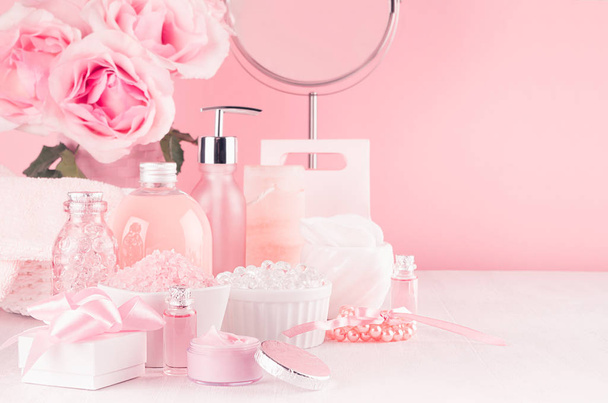 Modern youth bathroom or dressing table design in pastel pink color -  flowers, cosmetic products, bath accessories, jewelry, round mirror on white wood board. - Фото, изображение