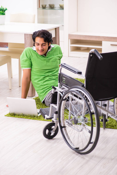 jonge knappe man in rolstoel thuis  - Foto, afbeelding