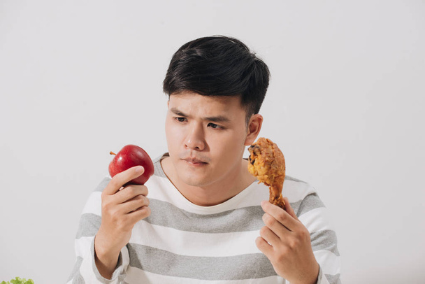 Homme ayant le choix difficile entre une alimentation saine et malsaine - Photo, image