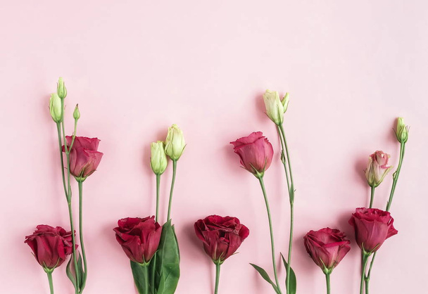 bovenaanzicht van mooie rode eustoma bloemen op roze achtergrond - Foto, afbeelding