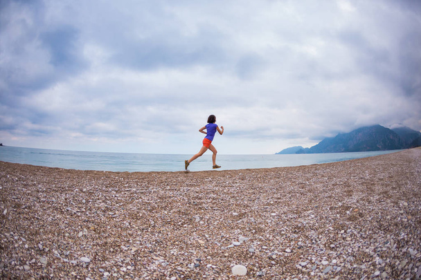 The girl runs along the sandy beach. - Zdjęcie, obraz