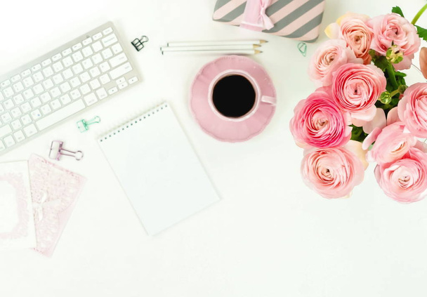 female workspace with keyboard, ranunculus flowers and pink cup of coffee - Photo, image