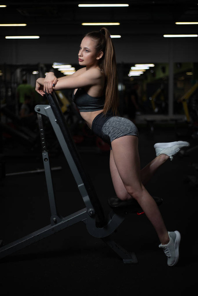 Onun vücudundan gösterilen bankta spor salonunda poz fitness kız - Fotoğraf, Görsel