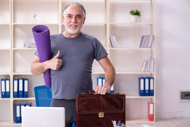 White bearded old man employee doing exercises in the office  - Photo, Image