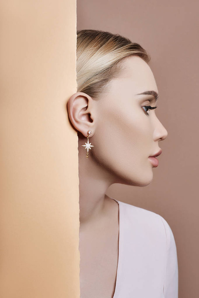 Earrings and jewelry in ear of a sexy blonde woman pressed again - Фото, изображение