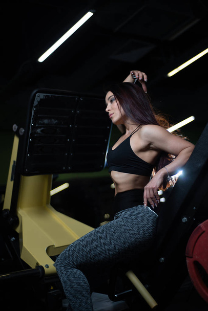 Fitness girl posing in the gym, showing off her body and relaxing after a workout - 写真・画像