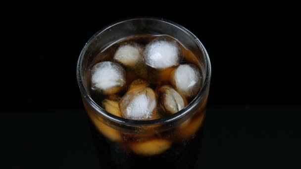 Bulles de cola froid dans un long verre transparent avec glace sur fond noir vue rapprochée
. - Séquence, vidéo