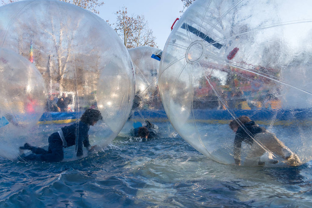 Junge Jungen spielen Spaß in großen, durchsichtigen Bällen auf dem Wasser - Foto, Bild