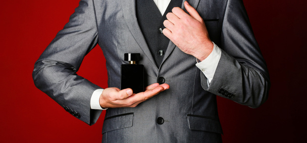 Man perfume, fragrance. Masculine perfume. Perfume or cologne bottle. Male fragrance and perfumery, cosmetics. Bearded man holding up bottle of perfume. Fashion cologne bottle - Photo, Image