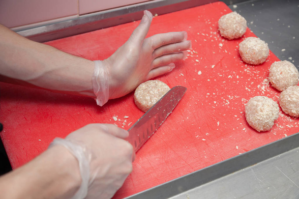 Ręce szefa kuchni w rękawicach tworząc kotlety kurczaka z nożem - Zdjęcie, obraz