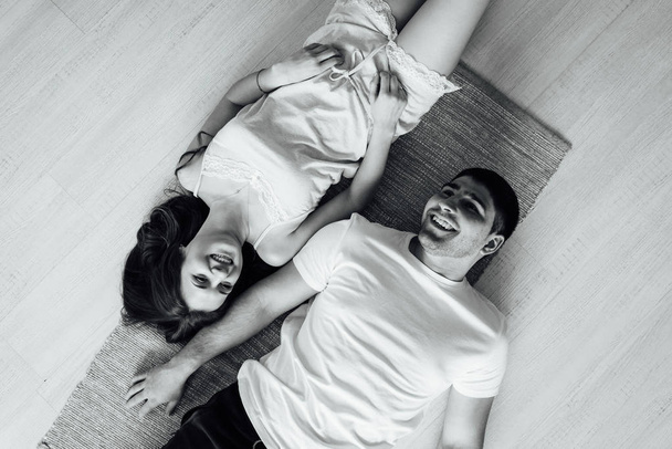 Γελάει νέοι στο πιτζάμες παιχνιδιάρικα ποζάρει στο καναπέ. Ευτυχισμένο ζευγάρι χαμογελώντας πρωί - Φωτογραφία, εικόνα