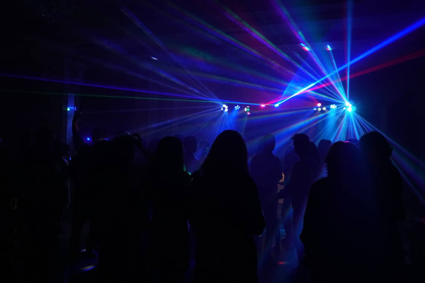Multitud de personas bailando bajo la luz láser disco
 - Foto, Imagen