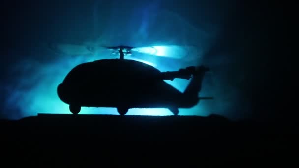 Silhouet van militaire helikopter klaar om te vliegen vanaf conflictgebied. Nacht beelden versierd met helikopter starten in woestijn met mistige afgezwakt achtergrondverlichting. Selectieve aandacht. - Video