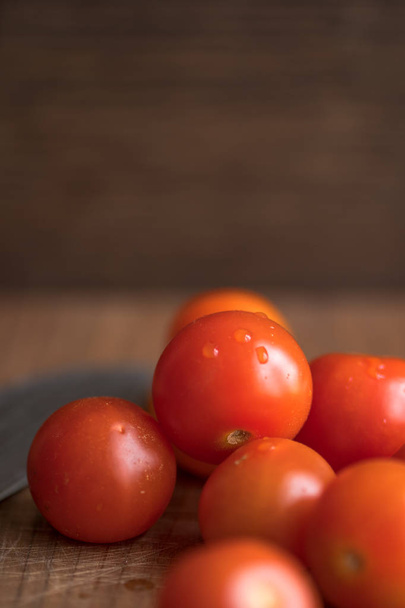 Fresh tomatoes on wooden table over bokeh background white knife beside - Fotoğraf, Görsel