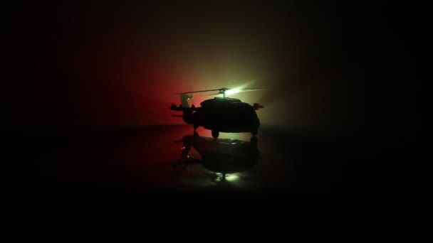 Sylwetka wojskowego helikoptera gotowy do lotu od strefy konfliktu. Ozdobione noc nagrania śmigłowca począwszy od pustyni z mglisty stonowanych podświetlany. Selektywny fokus. - Materiał filmowy, wideo