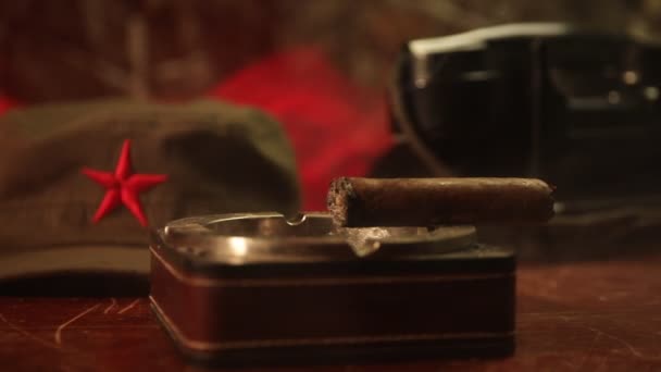 Close up van een Cubaanse sigaar en asbak op de houten tafel. Communistische dictator commandant tabel in donkere kamer. Generaal van het leger is werk tafelconcept. Illustraties decoratie - Video