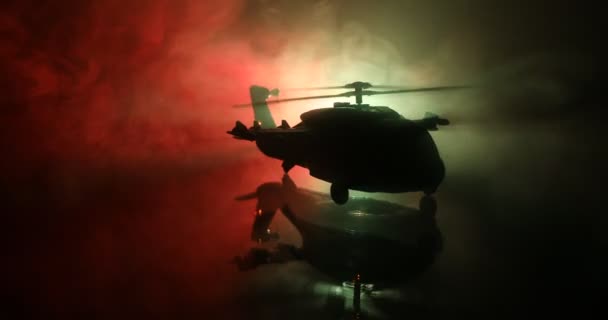 Sylwetka wojskowego helikoptera gotowy do lotu od strefy konfliktu. Ozdobione noc nagrania śmigłowca począwszy od pustyni z mglisty stonowanych podświetlany. Selektywny fokus. - Materiał filmowy, wideo
