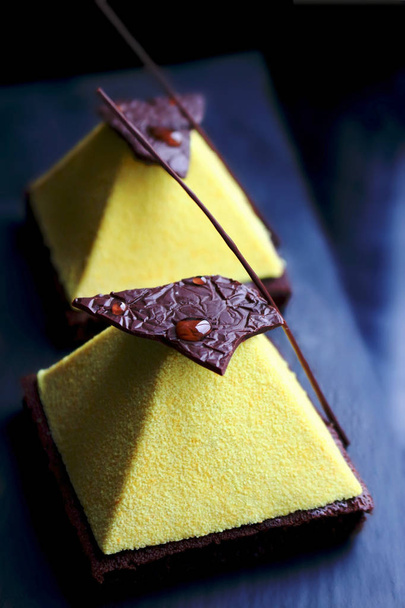 Deser żółty piramidy na ciemnym tle brownie - Zdjęcie, obraz