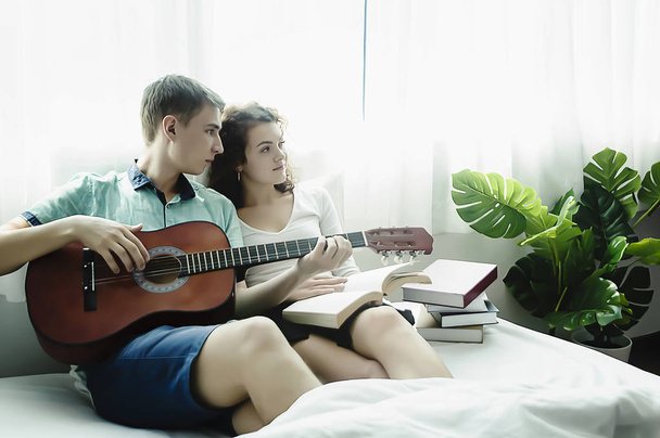 Romanttinen nuori pari soittaa kitaraa sängyssä yhdessä
. - Valokuva, kuva