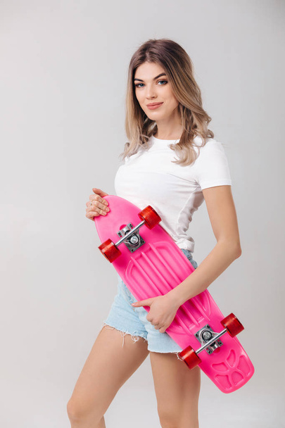 beautiful woman in white t-shirt with pink skateboard - Foto, imagen