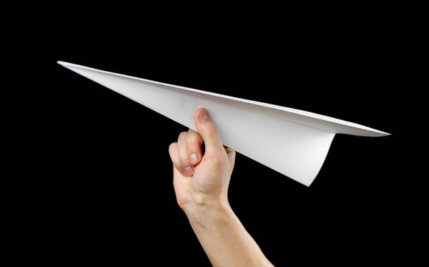 Hand holding a white paper airplane. Close up. Isolated on black - Foto, Imagen