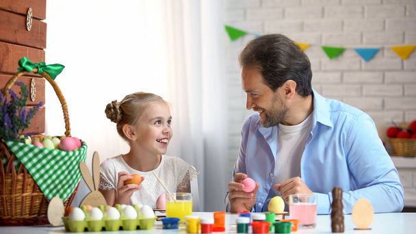 Happy dad and little girl looking at each other, holding easter eggs, having fun - Foto, imagen