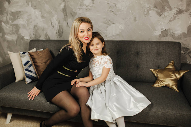 Mother and daughter at home. Beautiful little girl and elegant mom - Valokuva, kuva
