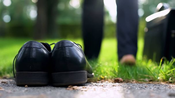 Czarne buty, stojąc na trawie, biznesmen chodzenia boso w parku radzi sobie stresu - Zdjęcie, obraz